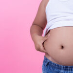 Obese boy who is overweight on a pink background.